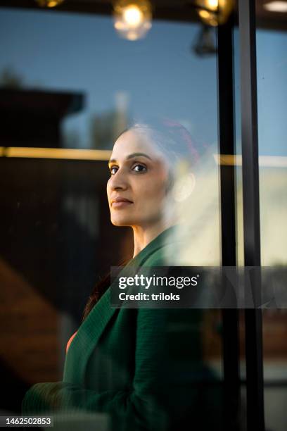 businesswoman looking away through glass window - women wearing see through clothing stockfoto's en -beelden