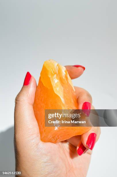 woman holding a rough orange calcite crystal - calcite stock pictures, royalty-free photos & images