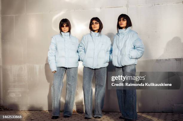 The Triplets wearing a light blue puffer jacket, blue denim jeans, and sunglasses outside Holzweiler, during the Copenhagen Fashion Week...