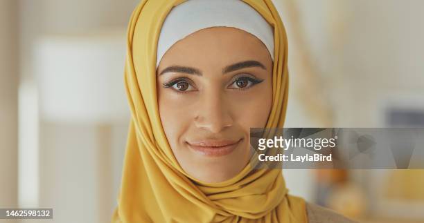 glückliche, porträtierte und muslimische frau, lächelnd und zufrieden in ihrem zuhause, sorglos und chillend vor verschwommenem hintergrund. gesicht, islamisch und mädchen entspannen sich in einem wohnzimmer und genießen einen ruhigen freien tag drinn - portrait frau arabisch frontal stock-fotos und bilder