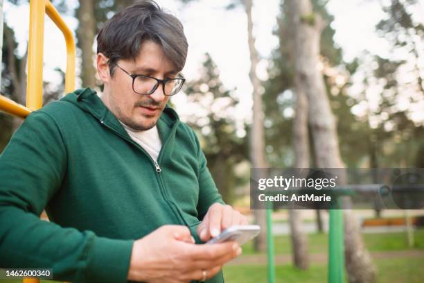 hombre mirando un teléfono inteligente durante la aptitud al aire libre - checking sports fotografías e imágenes de stock