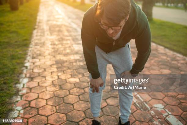 uomo stanco dopo aver corso all'aperto al tramonto - debolezza foto e immagini stock