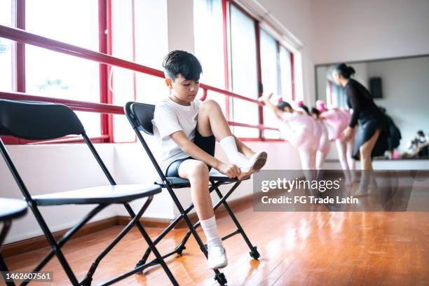 boy ballet dancer putting on shoes before practicing - boy ballet stock pictures, royalty-free photos & images