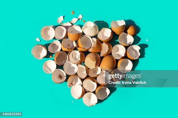 pile of shells from beige brown easter eggs in the shape of a heart on a pastel green turquoise color background. easter minimal concept. - easter egg colour isolated stock-fotos und bilder