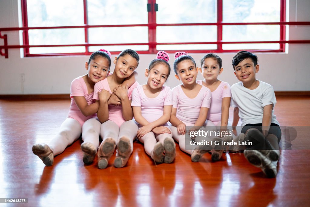 Porträt von Ballettschülern, die im Tanzstudio auf dem Boden sitzen