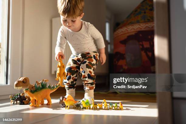 caucasian toddler boy playing with dinosaur toys - dinosaur toy i stock pictures, royalty-free photos & images