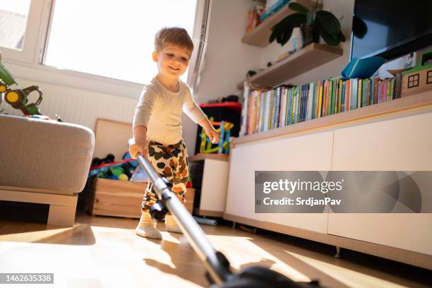 toddler boy playing with a vacuum cleaner in the living room - organizing playroom stock pictures, royalty-free photos & images