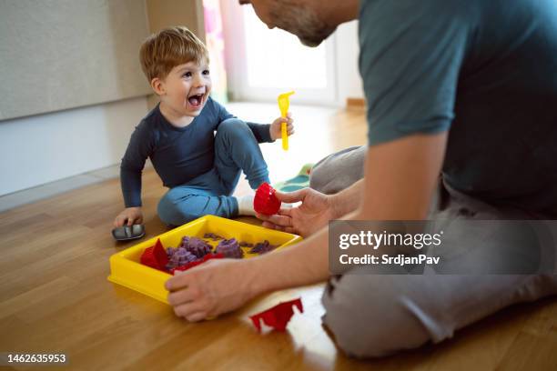 kaukasischer vater und sein kleiner sohn spielen zusammen mit hydrophober sand - sandkasten stock-fotos und bilder