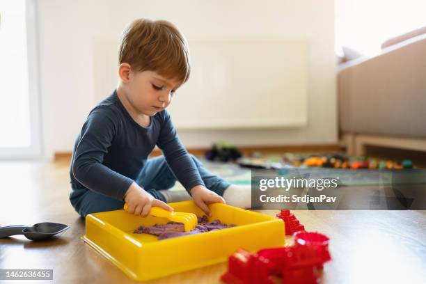 toddler boy playing with hydrophobic sand - sand pail and shovel stock pictures, royalty-free photos & images