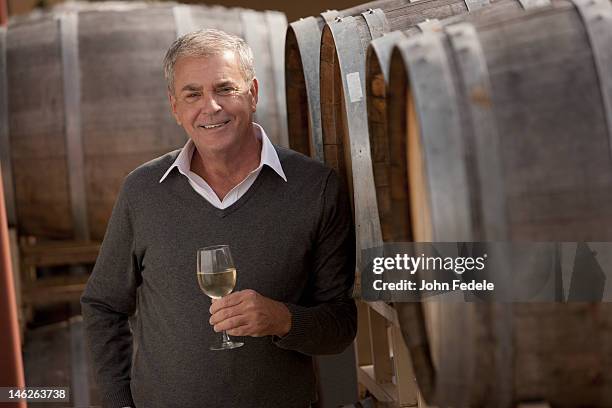 hombre caucásico de beber vino cerca de cilindro de madera - wine maker fotografías e imágenes de stock