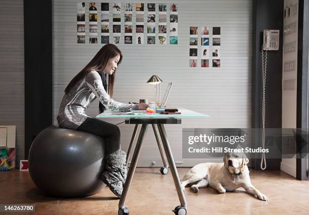 japanese businesswoman sitting on exercise ball and working at desk - fitness ball stock pictures, royalty-free photos & images