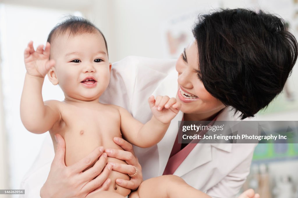 Medico tenendo sorridente bambino in ufficio del medico