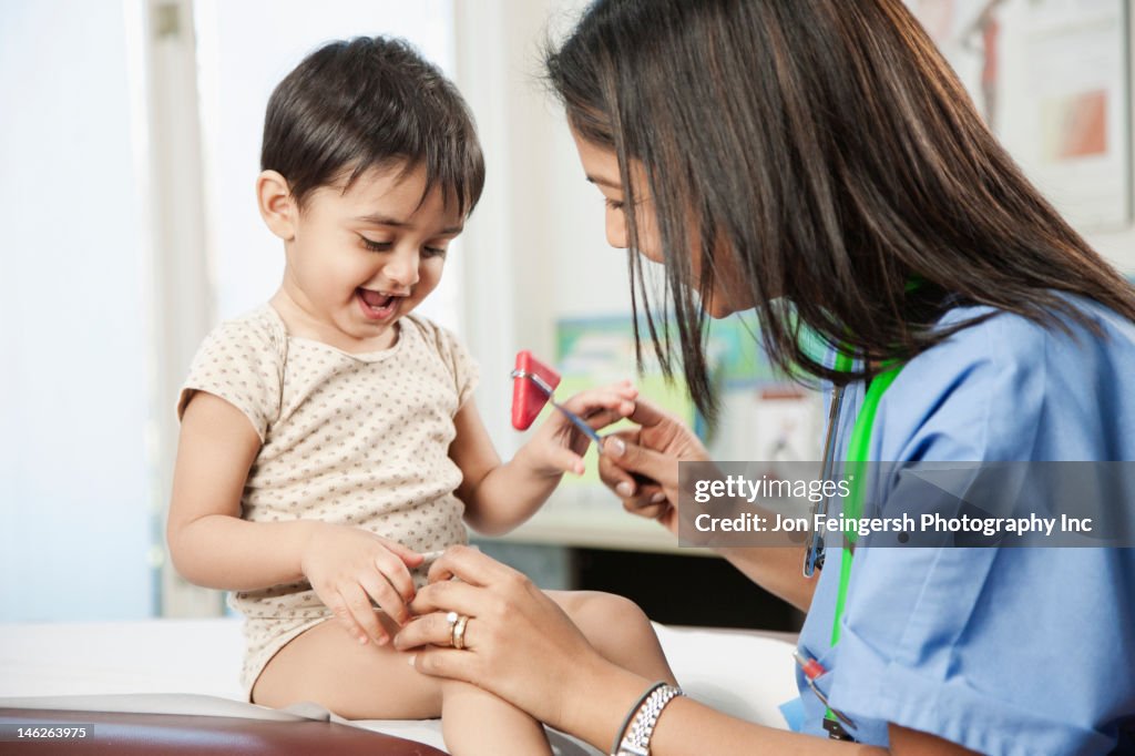 Indian doctor testing baby's reflexes in doctor's office