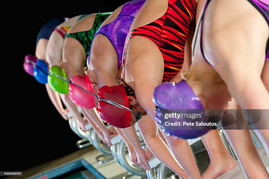 Swimmers preparing to dive off starting blocks