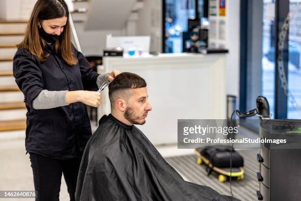 a young man is having a haircut in a barbershop. - salon international stock pictures, royalty-free photos & images