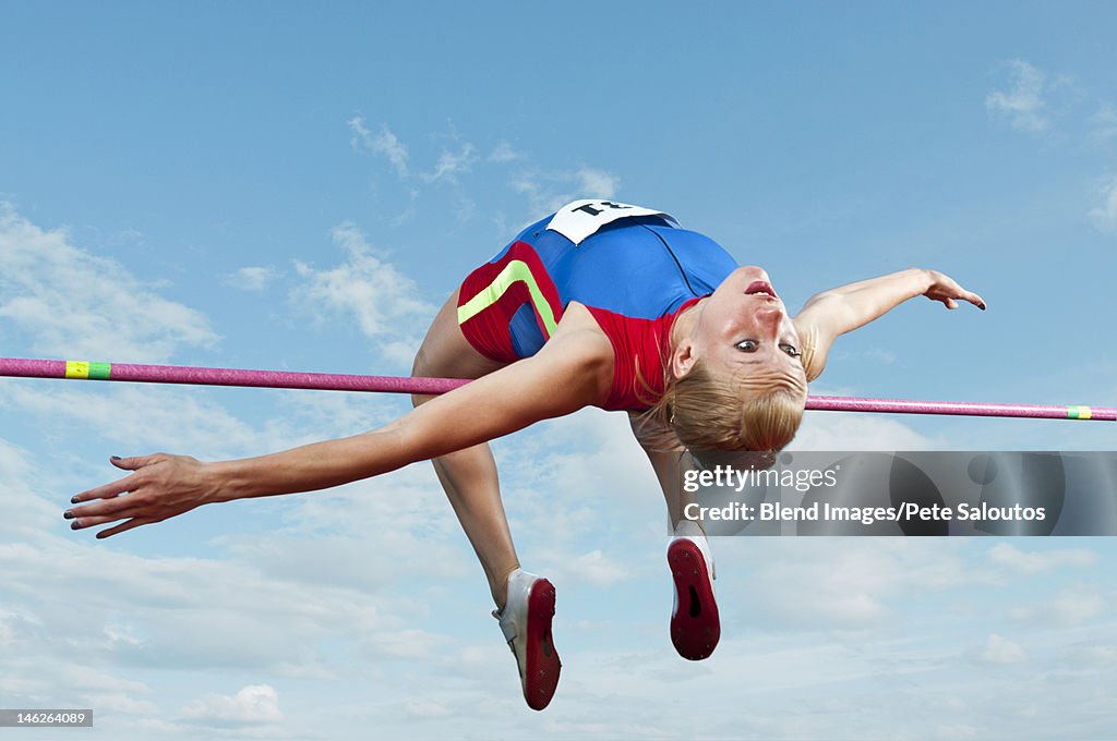 Caucasian athlete jumping over bar