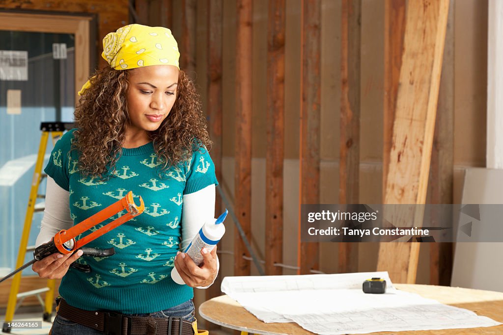 Hispânico Mulher a segurar caulking Arma