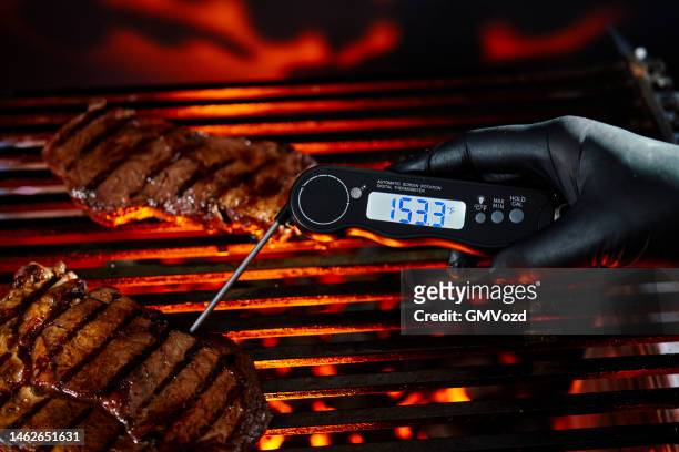 food safety - checking the right temperature inside grilled steak on bbq grill - digital thermometer stock pictures, royalty-free photos & images