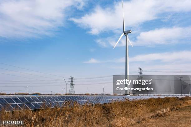 view of wind turbine energy generaters on wind farm, with solar panels underneath. - turbine stock pictures, royalty-free photos & images