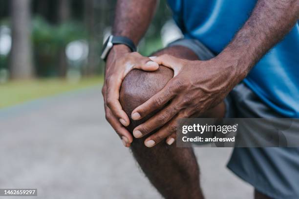 with hands on knee pain - pain stockfoto's en -beelden