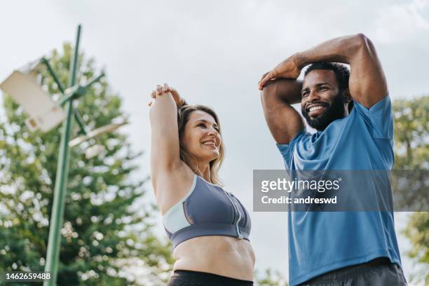 coppia di amici che si allungano per fare esercizi fisici - attività fisica foto e immagini stock