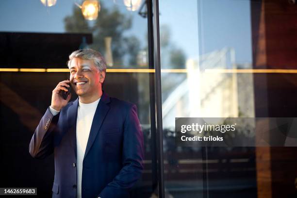 cheerful businessman using mobile phone at office - india office stock pictures, royalty-free photos & images