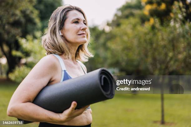 femme mûre qui va pratiquer l’exercice physique avec un tapis d’exercice - yoga rug photos et images de collection