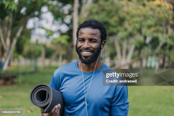 portrait of a man going to exercise holding exercise mat looking at camera and smiling - yoga rug stock pictures, royalty-free photos & images