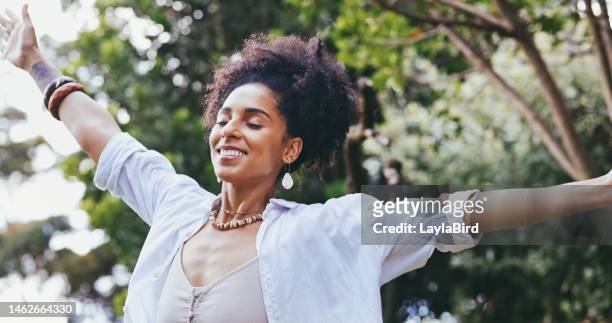 happy, black woman, smile and freedom for fresh air, relaxation or breathing in the nature outdoors. african american female enjoying holiday vacation, travel or trip with arms out in the forest - fresh air breathing stockfoto's en -beelden