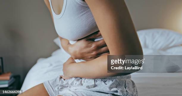 menstruation, stomach ache and hands of woman in bedroom for indigestion, cramps and illness. frustrated, gas and stress with girl on bed for constipation, bloating and intestine problems at home - smärta bildbanksfoton och bilder