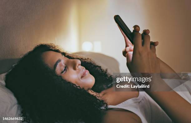 femme noire, téléphone et lit avec heureux pour les sms, la communication ou l’application de chat dans la maison. fille, détente et chambre avec smartphone, lecture ou médias sociaux pour les rencontres en ligne, flirter et rechercher l’amour - dating app photos et images de collection