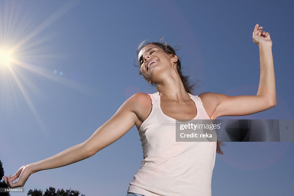 Happy young woman under blue sky