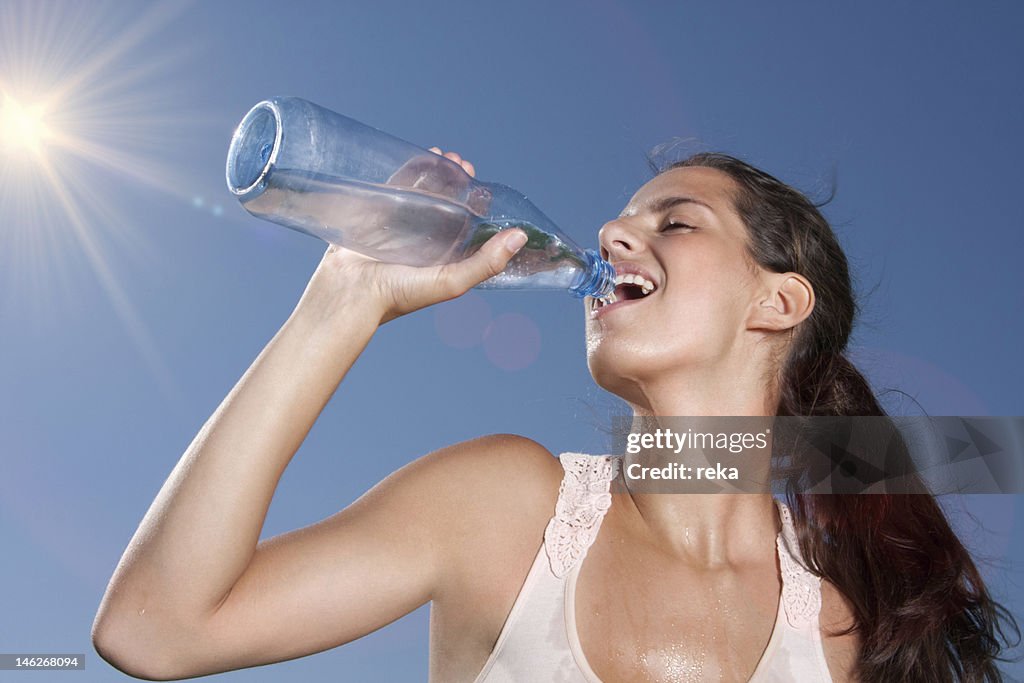 Young woman drinking water from bottle outdoors