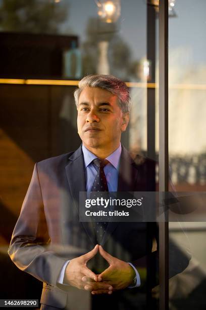thoughtful businessman looking through glass window - gesturing stock pictures, royalty-free photos & images