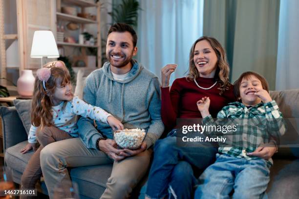 glückliche familie genießt auf dem sofa - family tv stock-fotos und bilder