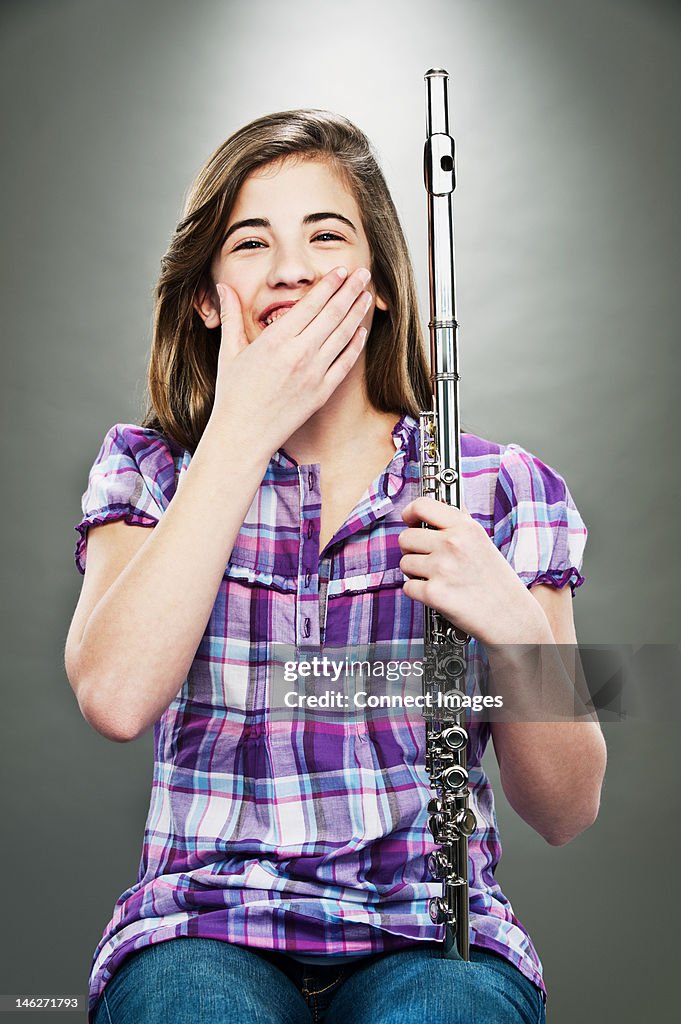 Portrait of young teenage girl laughing and holding flute