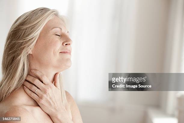 mujer madura touching cuello - mujer 50 años fotografías e imágenes de stock