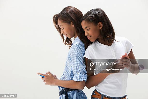 african american sisters using cellphones, studio shot - two people studio shot stock pictures, royalty-free photos & images