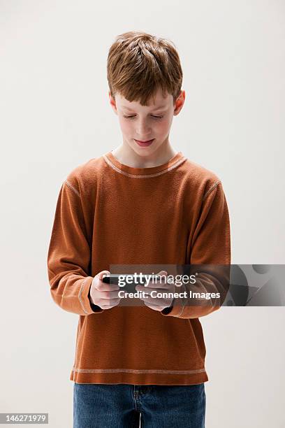 boy in brown sweater playing hand held video game, studio shot - kid studio shot stock pictures, royalty-free photos & images