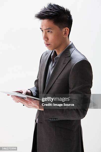 young asian businessman holding digital tablet, studio shot - asian man studio shot stock pictures, royalty-free photos & images