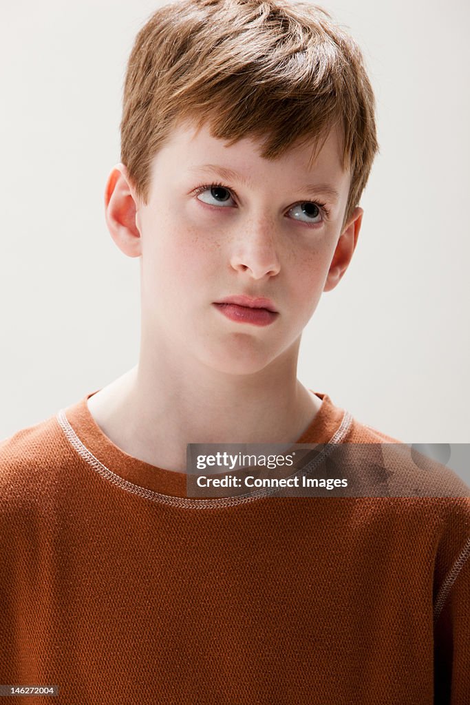 Boy in brown sweater rolling eyes, studio shot