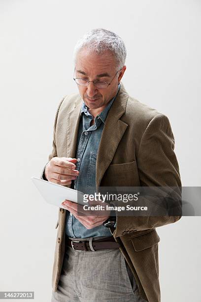 mature man looking at digital tablet, studio shot - man studio shot stock pictures, royalty-free photos & images