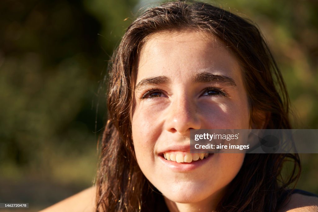 Beautiful young teenage girl with beautiful eyes, bushy eyebrows and wide smile with wet hair just out of the water