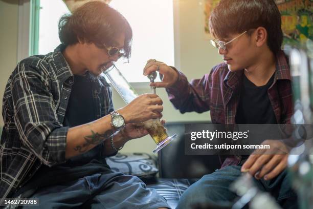 young man and his friend smoking marijuana with glass bongs - very young thai girls stock pictures, royalty-free photos & images