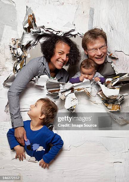 happy family busting through a wall - breaking through wall stockfoto's en -beelden