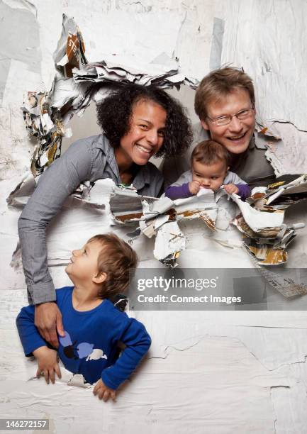 happy family busting through a wall - appear stock pictures, royalty-free photos & images