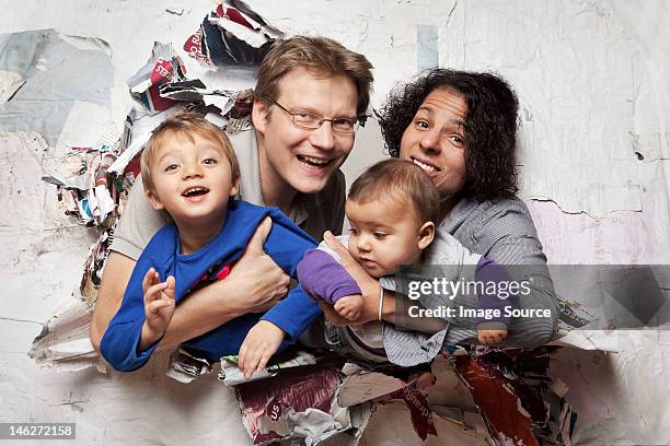 happy family busting through a wall - breaking through wall stockfoto's en -beelden