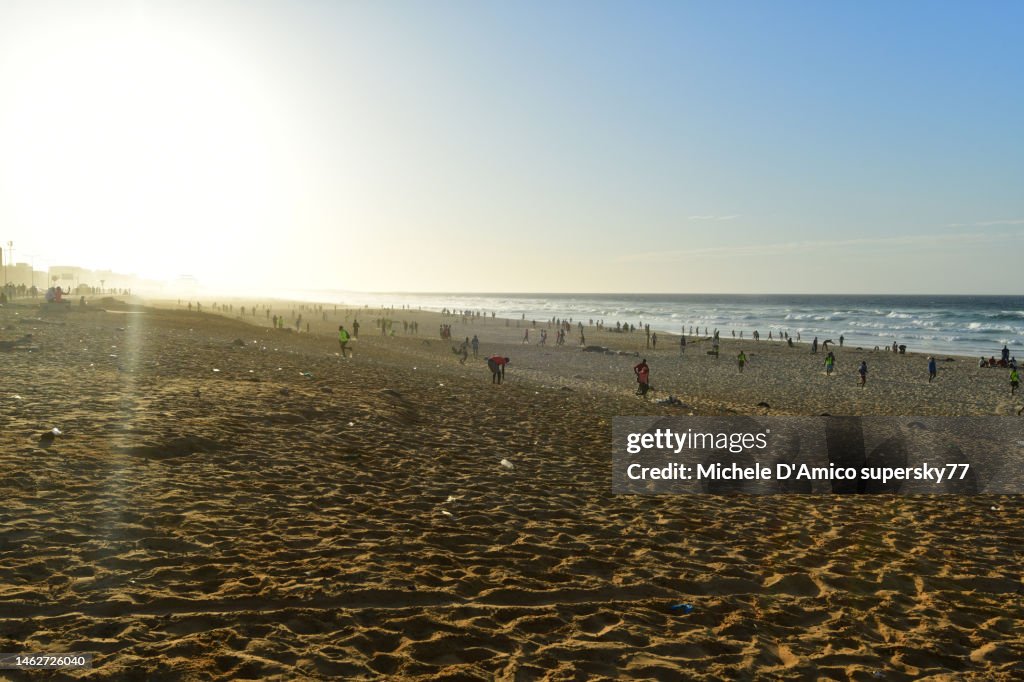 Men playing football on the broad sandy beach in Dakar