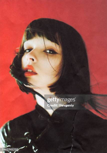 brunette asian woman in studio on red background. fashion model. scanned film photo. dust and scratches on photo. - asian woman black hair bangs studio stock pictures, royalty-free photos & images