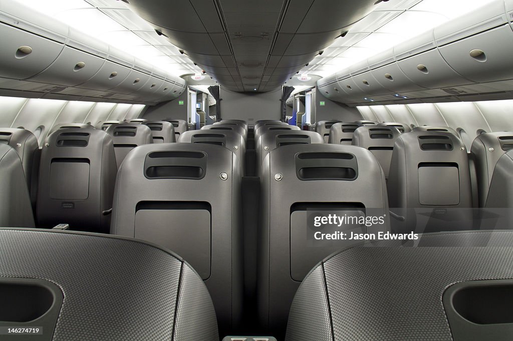 Rows of empty graphite business class passenger seats in a plane cabin.